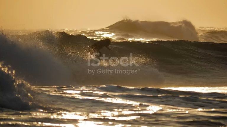 Surfer on a golden wave at sunset